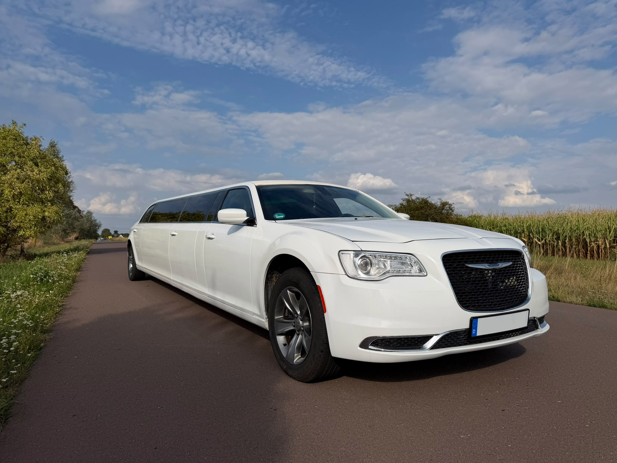 Weiße Chrysler 300 Stretchlimousine auf einer Landstraße